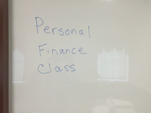 "Handwritten 'Personal Finance Class' text written on a whiteboard used during a financial literacy lesson."