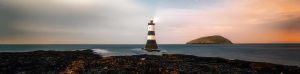lighthouse with rocks and evening sky.
