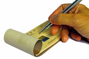 hand holding pen over check book, writing check.