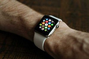 Smartwatch on a person's wrist displaying app icons, symbolizing how technology replaces traditional products.