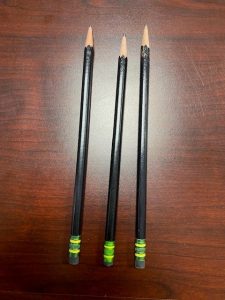 Three sharpened pencils, lined up on a wooden desk, representing simple and practical financial planning choices