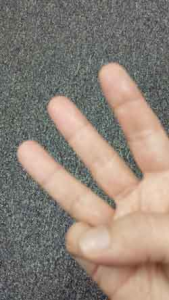 Hand holding up three fingers on a neutral background